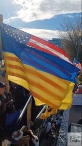 A crowd of people holding flags in front of a fence.