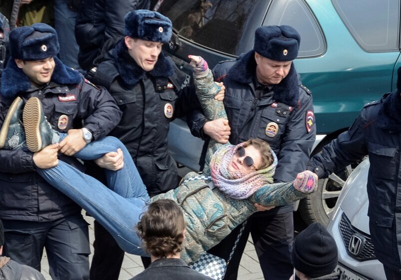 A group of police officers holding up a person.