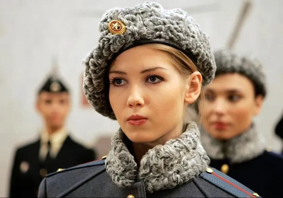 A woman in military uniform and hat with other people.